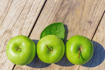 Freshly cropped geen apples on wooden table, top view, copsy space