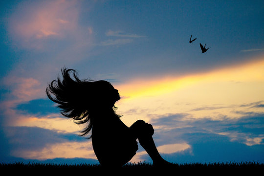 little girl with her hair in the wind at sunset