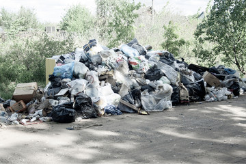 Illegal dump near the country sand road in the country on sunny day. Trash pollution in the nature. Dirty dump near forest woods. Black and white