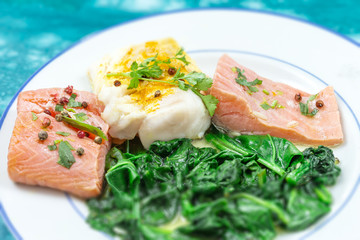 Cod and Salmon fillet with rice and spinach garnish. Fish steak. Lemon salmon on white plate on wooden background