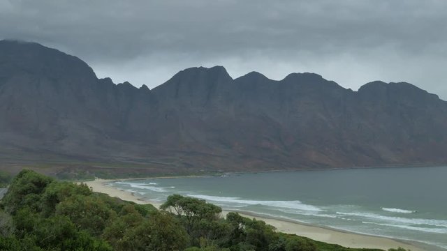 Waves running onto long stretch of pristine beach in beautiful setting, next to mountain, shot from high vantage point, South Africa.