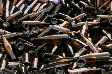 whole and broken brown bottles are scattered on gravel.Concept: waste recycling, disposal of garbage