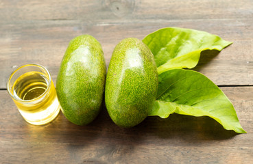 fresh avocado with leaves and oil on wood background