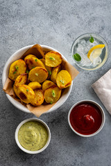 Baked potato wedges with cheese and herbs and tomato sauce on grey background - homemade organic vegetable vegan vegetarian potato wedges snack food meal.