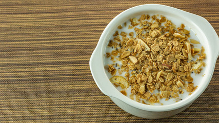 Morning food almond flakes  and milk in white bowl on wood table.