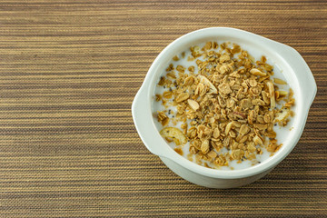 Morning food almond flakes  and milk in white bowl on wood table.