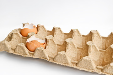 Carton packaging for eggs with broken eggshell on a light background. Organic concept