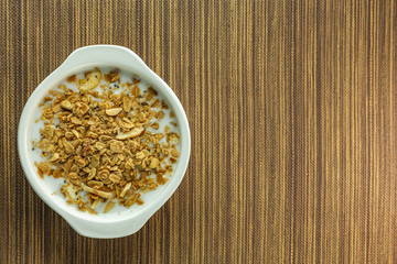 Morning food almond flakes  and milk in white bowl on wood table.