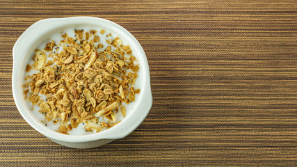 Morning food almond flakes  and milk in white bowl on wood table.