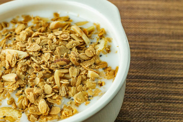 Morning food almond flakes  and milk in white bowl on wood table.