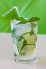 A glass of mint lemonade. Cold fresh drink on green beige background. Shallow depth of field