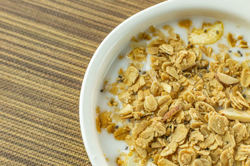 Morning food almond flakes  and milk in white bowl on wood table.