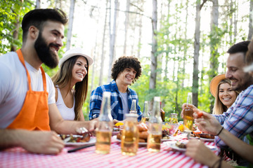 Happy friends camping and having a barbecue in nature