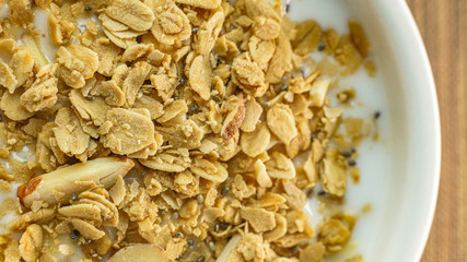 Morning food almond flakes  and milk in white bowl on wood table.