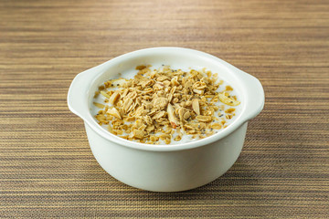 Morning food almond flakes  and milk in white bowl on wood table.