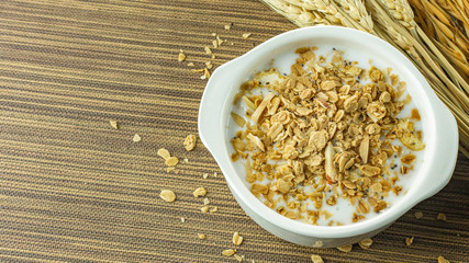 Morning food almond flakes  and milk in white bowl on wood table.