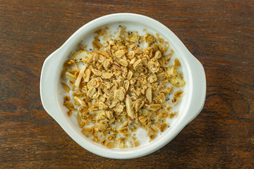 Morning food almond flakes  and milk in white bowl on wood table.