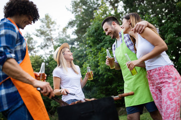 Group of happy friends eating and drinking beers at barbecue dinner