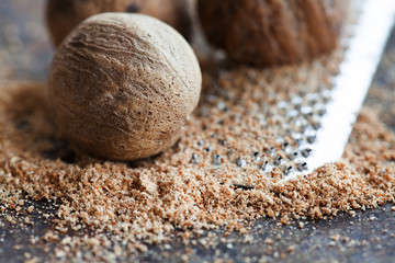 Making nutmeg powder process. Nuts silver grater. Kitchen still life photo. Shallow depth of field, aged brown rusty background. Selective focus. - obrazy, fototapety, plakaty