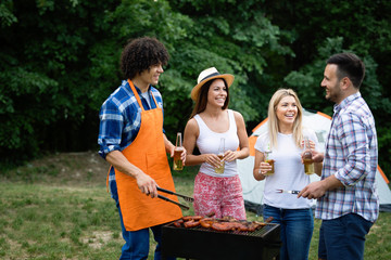 Friends having a barbecue party in nature while having fun