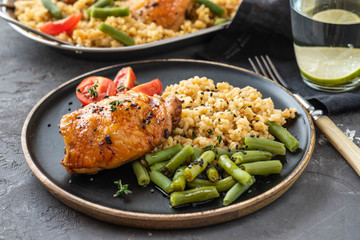 Grilled chicken thighs with bulgur, asparagus beans and tomatoes. Delicious lunch. Copy space.