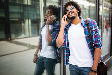 Close up portrait of laughing black young man talking on mobile phone and looking away