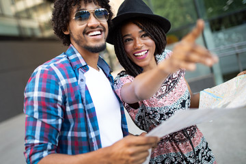 Happy young black couple of travellers holding map in hands