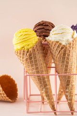 Assorted ice cream in sugar cones on pink background. Copy space.