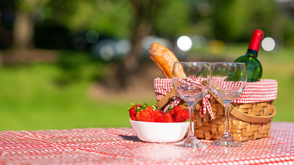 picnic basket checkered with a tablecloth wine, baguette, strawberry, glasses, banner