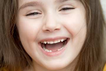 the close up portrait of little girl's face with missing front lower milk teeth in a smiling mouth