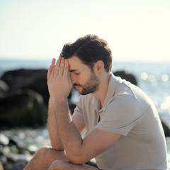 Praying man sitting on a sea beach