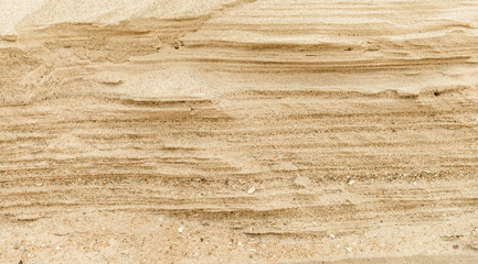 Naklejka na ściany i meble Layers of sand on the beach, soft sandstone at the shore. Abstract background texture