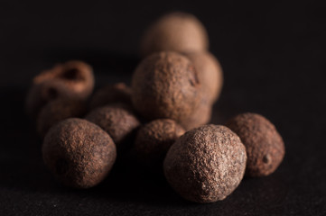 Black allspice in a pile on a dark background