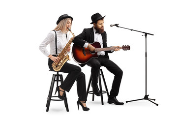 Young woman playing sax and a man playing an acoustic guitar