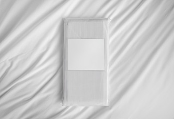 Striped fabric bedlinen items in the PVC bag with empty label against the white sheet.