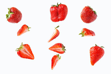 pieces and whole strawberries isolated on a white background in a chaotic manner .