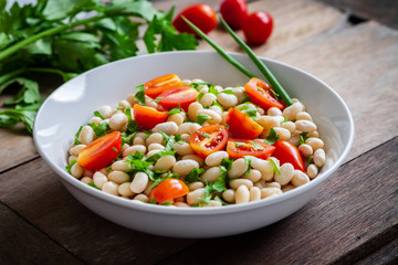 White bean salad with cherry tomatoes and parsley in bowl