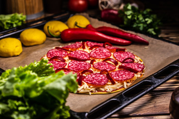 Raw pizza with cheese and salami