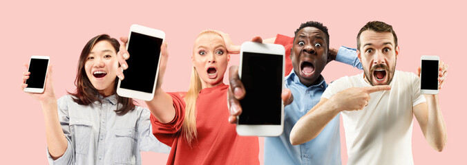 Portrait of people showing mobile phones isolated over coral background. Male and female models...