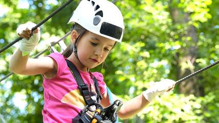 Cute preschool girl in climbing gear in a rope park, family outdoor activities, happy summer time, sports and an active lifestyle