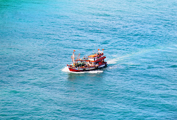 Fototapeta premium Fisherman ship in a open sea with blue clear water. Top view.
