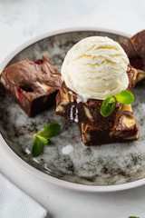 Chocolate brownie with vanilla ice cream, rasberry and mint on a white background. Copy space.
