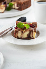 Cheesecake brownies with raspberry stacked on a white plate.