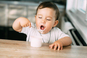 A little charming girl eats yogurt all smeared herself