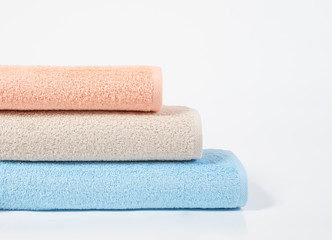 Stack of blue, beige and pink terry towels isolated