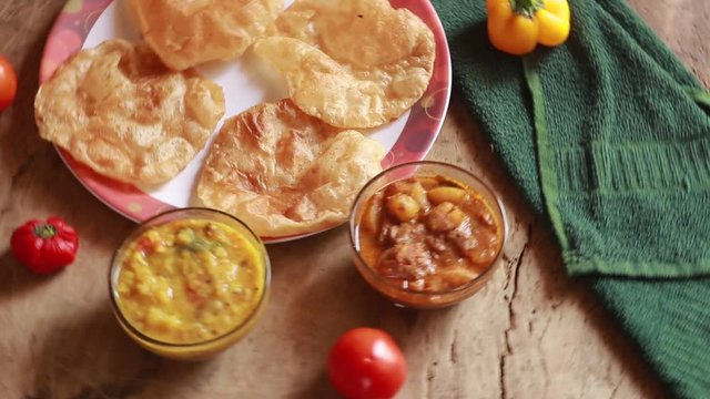 rotation Chole Bhature or Chick pea curry and Fried Puri served in terracotta crockery over wood background.