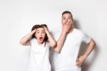 Shocked young couple on light background