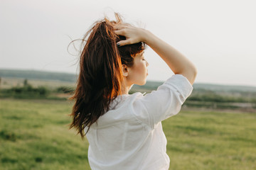 Close up portrait of beautiful carefree long hair girl in white clothes in field. Sensitivity to...