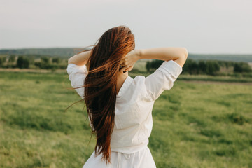 Close up portrait of beautiful carefree long hair girl in white clothes in field, view from back....