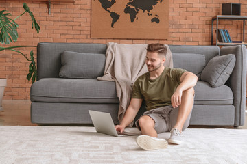 Handsome man with laptop resting at home